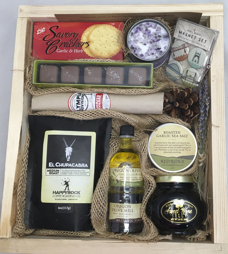 Sample box containing coffee, olive oil, balsamic vinegar, jam, garlic salt, salami, candle, magnet set, chocolate truffles, and crackers.