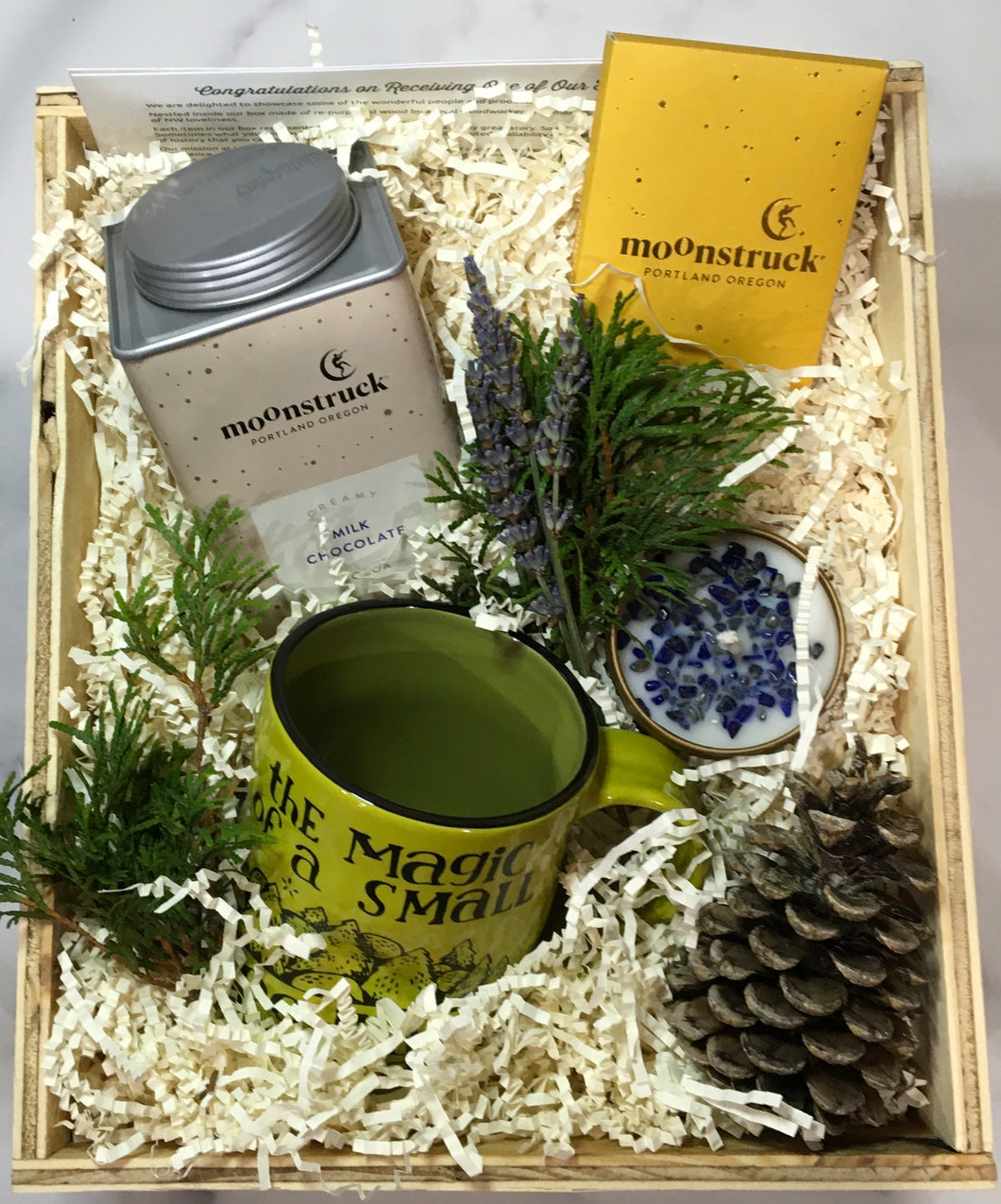 Sample box containing a mug, hot chocolate, chocolate bar, candle, and lavender bunch. 